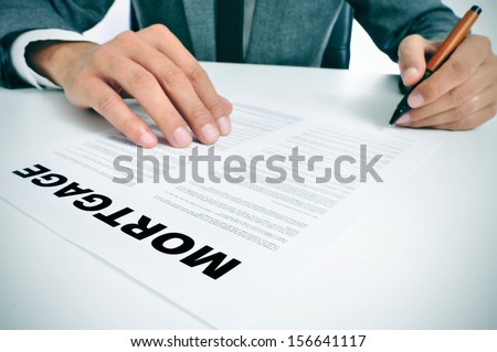 man wearing a suit sitting in a table signing mortgage loan contract