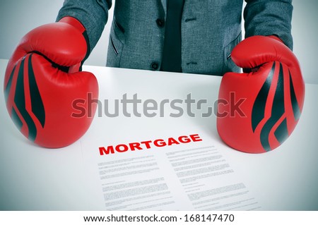 man wearing a suit and boxing gloves with a mortgage contract on his desk