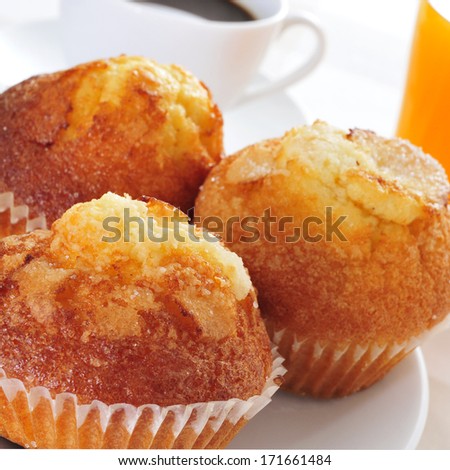 a plate with some magdalenas, typical spanish plain muffins, and a cup of coffee and a glass of orange juice