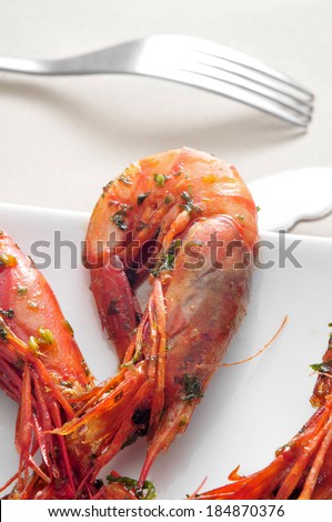 closeup of a plate with spanish shrimps cooked with garlic and parsley on a set table