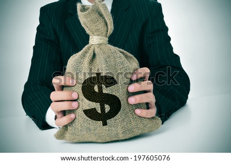 a man wearing a black suit holding a burlap money bag