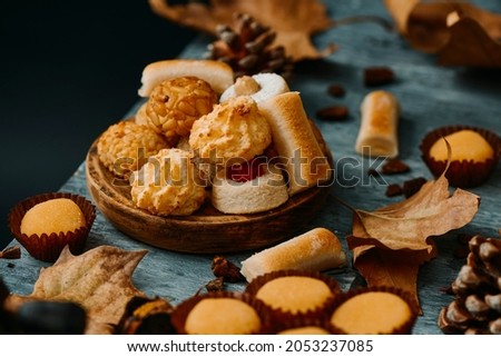 some different confections typicaly eaten in Spain on All Saints Day, such as Panellets, Huesos de Santo or Yemas de Santa Teresa, on a gray rustic table