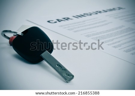 closeup of a car key and a car insurance policy
