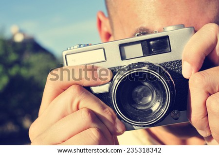 closeup of a young man taking a picture with an old camera outdoors