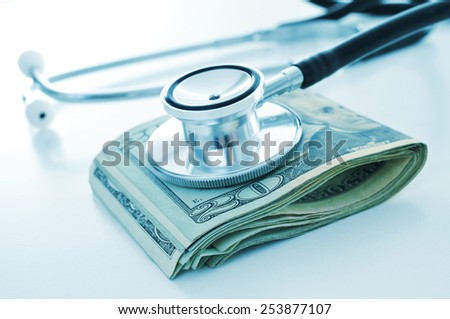 a stethoscope on a wad of US dollar bills, depicting the concepts of the health care industry or the health care costs