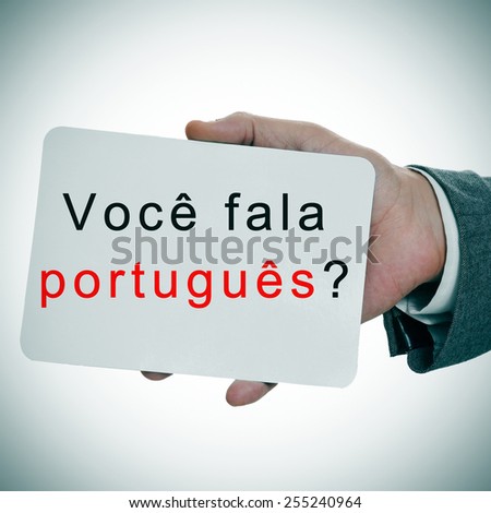 man hands showing a signboard with the sentence voce fala portugues? do you speak portuguese written in it