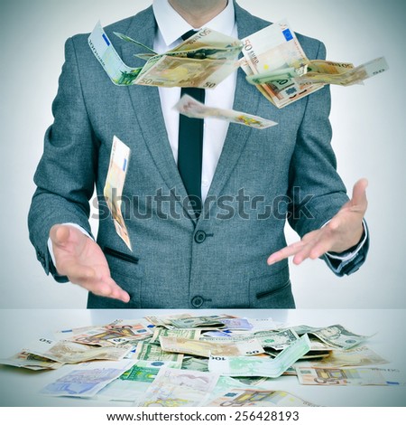 man in suit trying to catch money falling from the sky