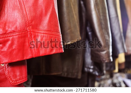 closeup of some used leather clothes, such as jackets and skirts, of different colors hanging on a rack in a flea market