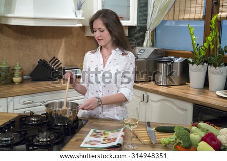 Young smiling woman preparing food and cooking in her kitchen.
