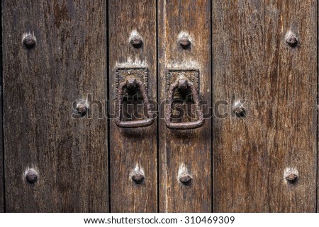 Old weather wooden door with rusty metal door pulls,  Medieval