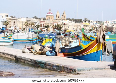 the fishing village of marsaxlokk in the maltese islands with a scenic view of the traditional wooden fishing boats and the church in the background