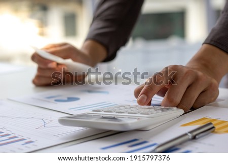 Businessmen use a calculator to calculate income and expenses in order to manage budgets to pay off credit card debt.