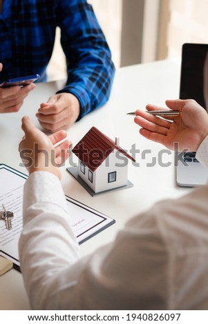 The real estate agent is explaining the house style to the clients who come to contact to see the house design and the purchase agreement, Mortgage loan approval home loan and insurance concept.
