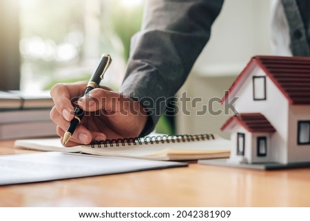 A real estate broker or insurance agent works with home models and home real estate sales contracts within the office, Mortgage loan approval home loan and insurance concept.