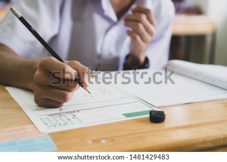 School / university Students hands taking exams, writing examination room with holding pencil on optical form answers paper sheet on desk doing final test in classroom. Education assessment Concept Stok fotoğraf © 