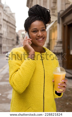 african american woman talking on the phone and holding a smoothie.