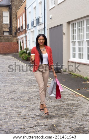 young woman walking with shopping bags and a take away coffee