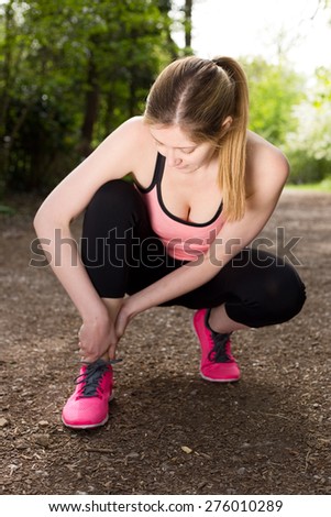 a young woman holding her ankle in pain after twisting it.
