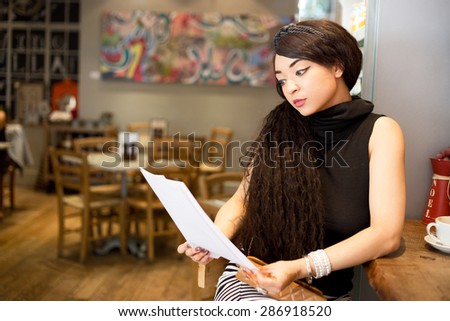 young woman reading papers in a coffee shop