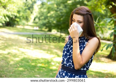 young woman with hay fever blowing her nose.