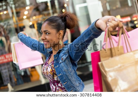 young woman holding shopping bags with arms outstretched