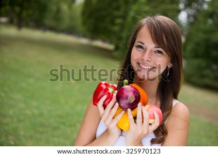 young woman outdoors holding fruit and vegetables