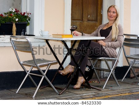 young woman sitting outside a bar having a drink.