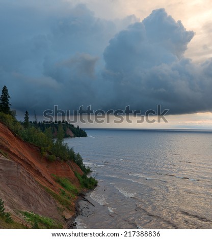 Majestic landscape with storm on the lake and huge thundercloud.