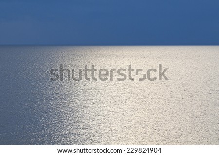 Sparkling lake surface at sunset. Simple natural landscape with  silvery lake and darkly blue sky.
