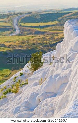 Hills with road on horizon and terraces covered with calcium with hot waterfall.