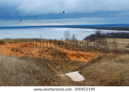 Windy April day on the shores of lake Onega in Russia, with two flying crows.