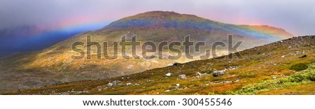 Alpine tundra after storm rainbow over mountains.