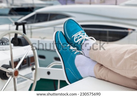 A pair of human legs in pants and bright blue topsiders on yacht deck background. Yachting