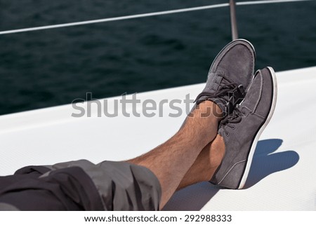 A pair of man legs in pants and topsiders on white yacht deck. Yachting