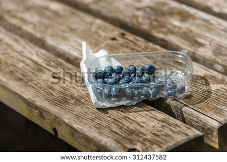 Blueberries in a plastic box on the wooden rustic table. Small GRIP