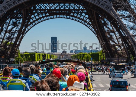 FRANCE, PARIS - JUNE 06: Tourists enjoy sightseeing tour on a hop-on-hop-off city bus in Paris on June 06, 2015. Bus is under The Eiffel tower.