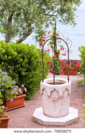italian flower garden with stone well. vertical shot