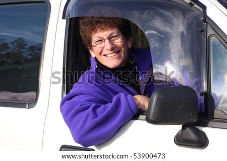 Senior woman smiling sitting in her car