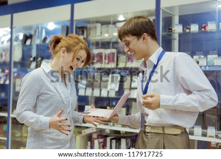 The seller-adviser shows the girl a computer
