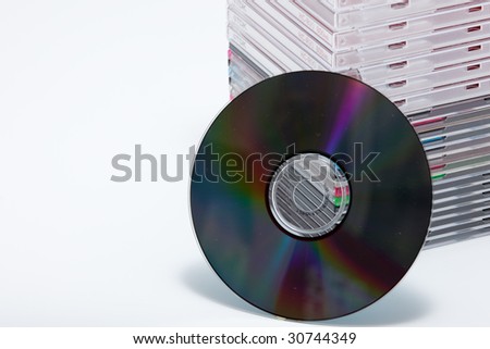 a blank dvd or cd with stack of empty cd cases on background