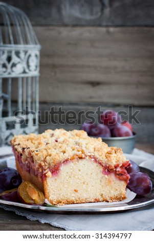 Plum cake on a metal tray next to the cage and a bowl of plums