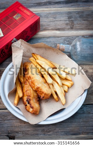 Fish and french fries with gravy on a paper