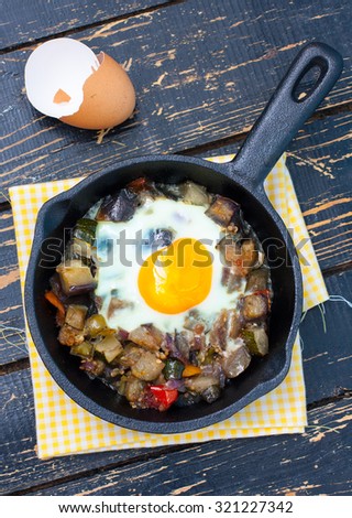 Vegetable stew with eggplant and egg in a batch cast iron pan, top view