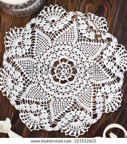 White openwork knitted cloth on a wooden table, top view, square image