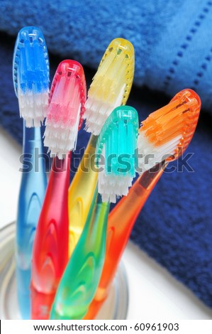 Five colorful toothbrushes in a water glass