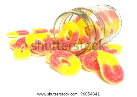 Peach flavored candy rings and glass jar on white background