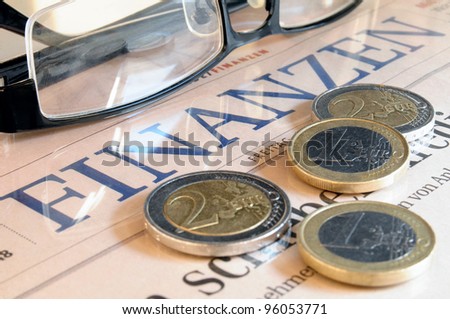 Euro coins , black glasses and the lettering Finances in German language
