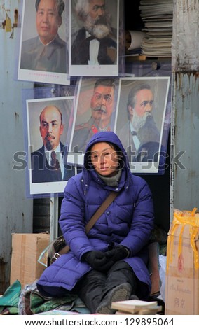 BEIJING, CHINA - CIRCA JANUARY 2013: Woman is selling portraits of communist dictators and ideologists on biggest and best-known  antiques market, \