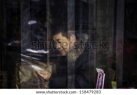BEIJING, CHINA - CIRCA JANUARY 2013: Man seen trough the window eating in Chinese street restaurant in Beijing, China.Millions of Chinese people eat street food every day.