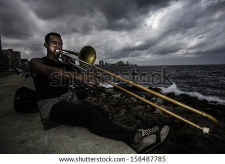 HAVANA, CUBA - CIRCA NOVEMBER 2006: Unidentified man playing trumpet by the ocean on circa November 2006.Havana attracts over a million tourists annually.
